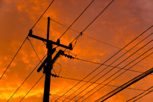 Telephone and electric pole with wires at sunset.